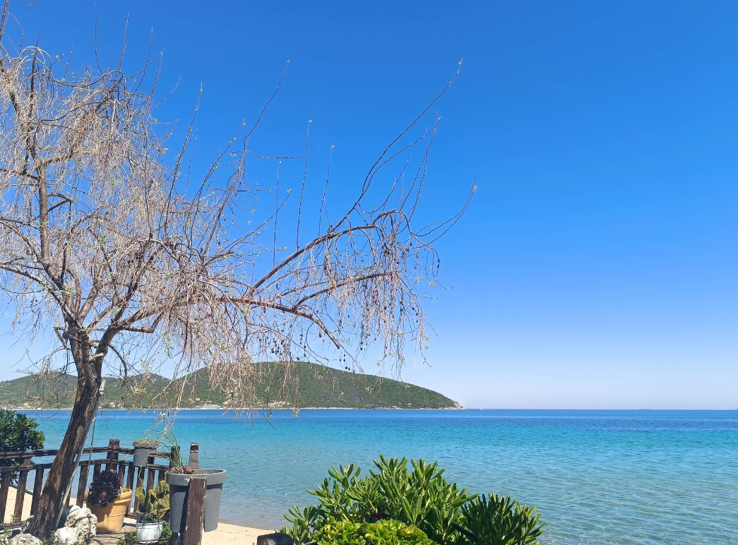 Пясъчен плаж в Неа Перамос с тюркоазено море и чадъри