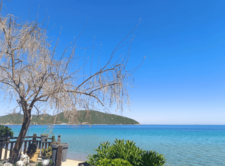 Пясъчен плаж в Неа Перамос с тюркоазено море и чадъри