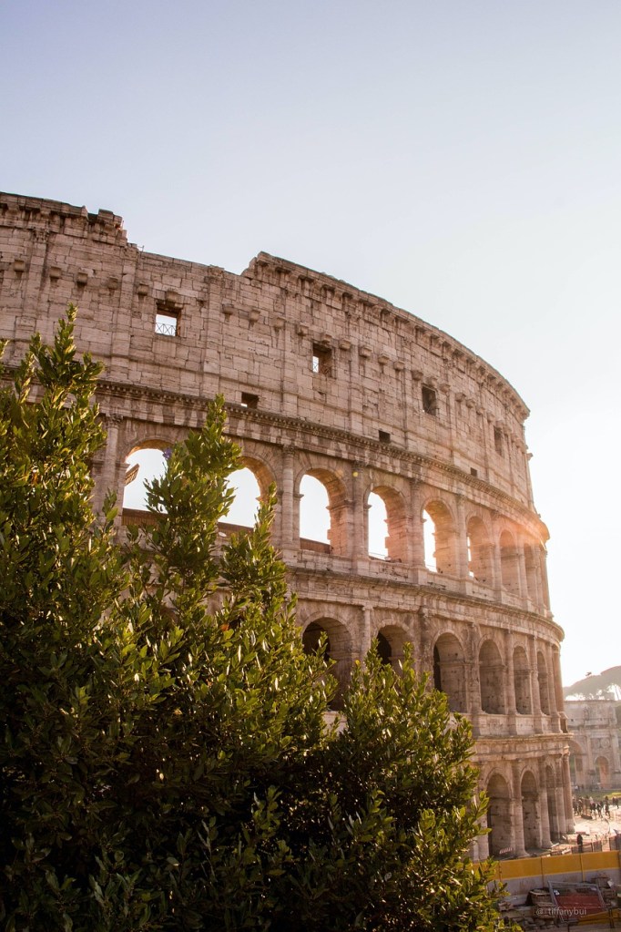 An iconic view of the ancient Roman Colosseum, bathed in golden sunlight, showcasing its remarkable architectural grandeur.